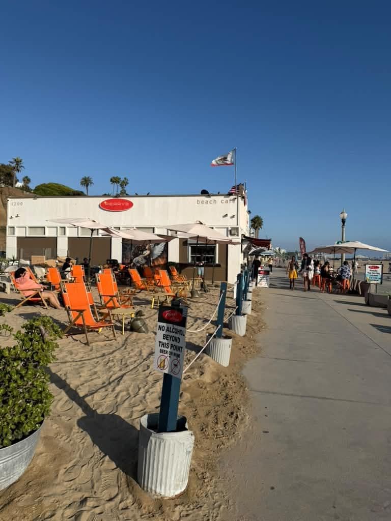 A beachside cafe with outdoor seating and a no alcohol sign.