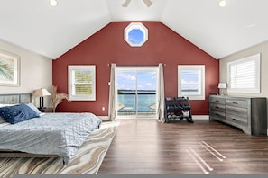 A bedroom with a large bed, a view of the sea through a sliding glass door, and a gym area with weights. - Oceanfront Serenity Sauna (Halifax)