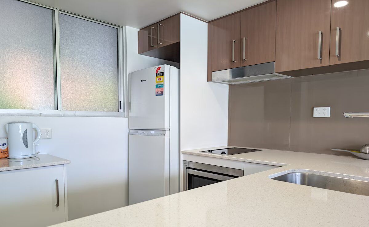 A compact kitchen with a refrigerator, a coffee maker, and a sink.