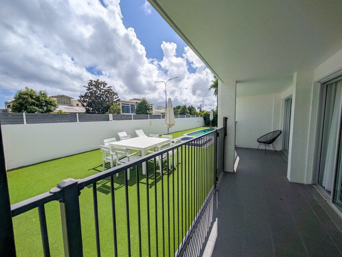 A balcony with a pool, outdoor furniture, and a view of the neighborhood.