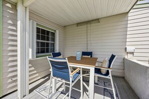 An outdoor patio with a table and chairs, a window, and a wall-mounted air conditioning unit. - 3BR, 2BA home in Fernandina Beach's North End, on Amelia Island (Fernandina Beach)