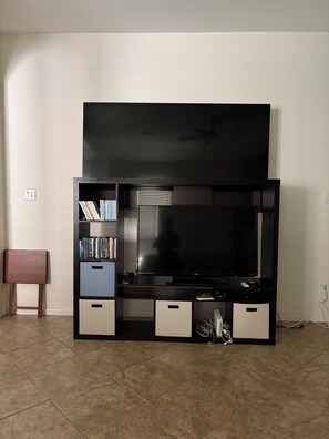 A living room with a large flat-screen TV, a bookshelf, and a small seating area. - Charming 3-bedroom house in peaceful Magnolia-baby crib-pet friendly (Magnolia)