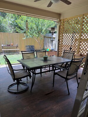 An outdoor patio with a table and chairs, a wooden fence, and a wooden deck. - Charming 3-bedroom house in peaceful Magnolia-baby crib-pet friendly (Magnolia)