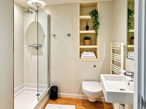 Un baño moderno con ducha envuelta en vidrio, inodoro y lavamanos.