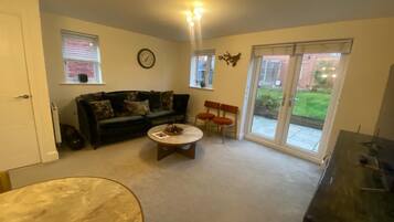 A living room with a sofa, a coffee table, and a television.