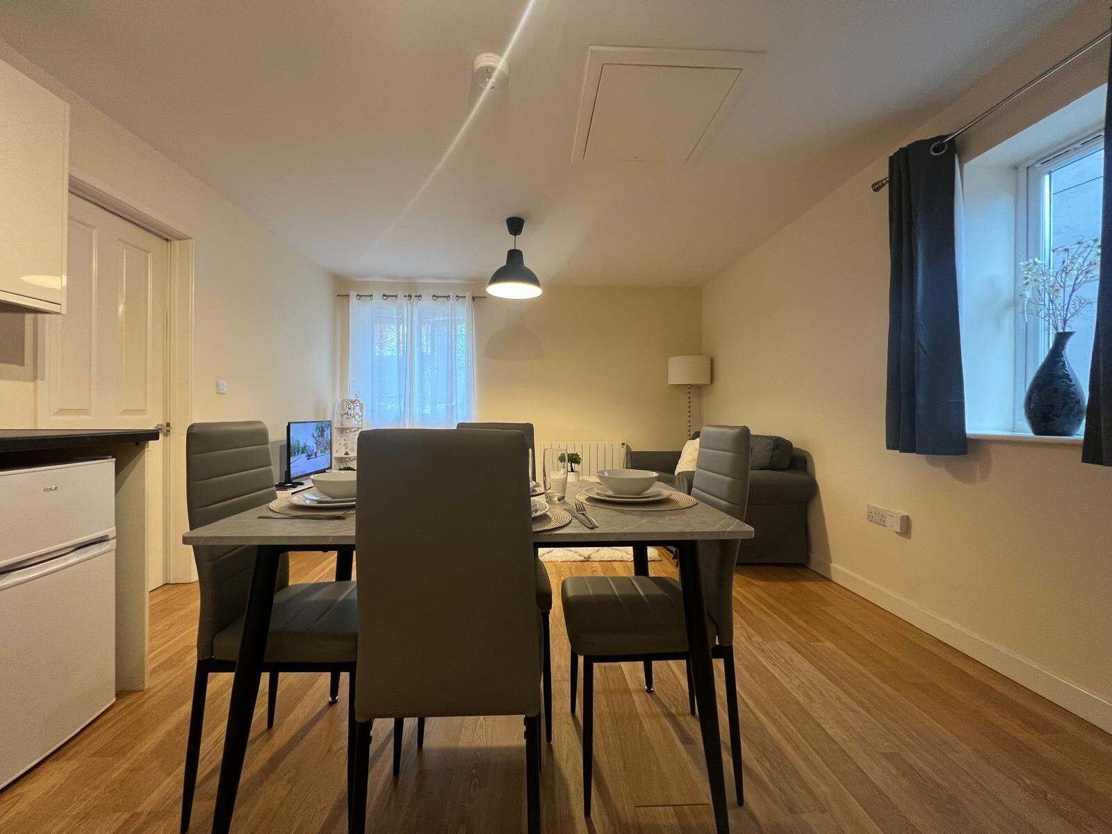 A compact living space with a dining area, kitchenette, and seating area.