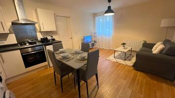 A modern apartment with a dining area, kitchen, and living space.