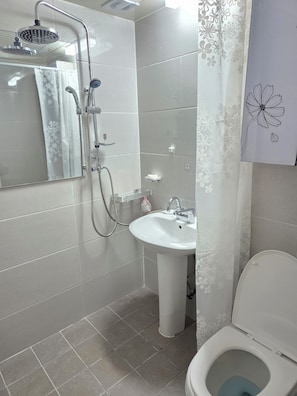 Un baño con ducha, lavamanos e inodoro.