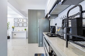 Eine moderne Küche mit einem Edelstahl-Kühlschrank, einer Kaffeemaschine und einem schwarzen Hängegestell.