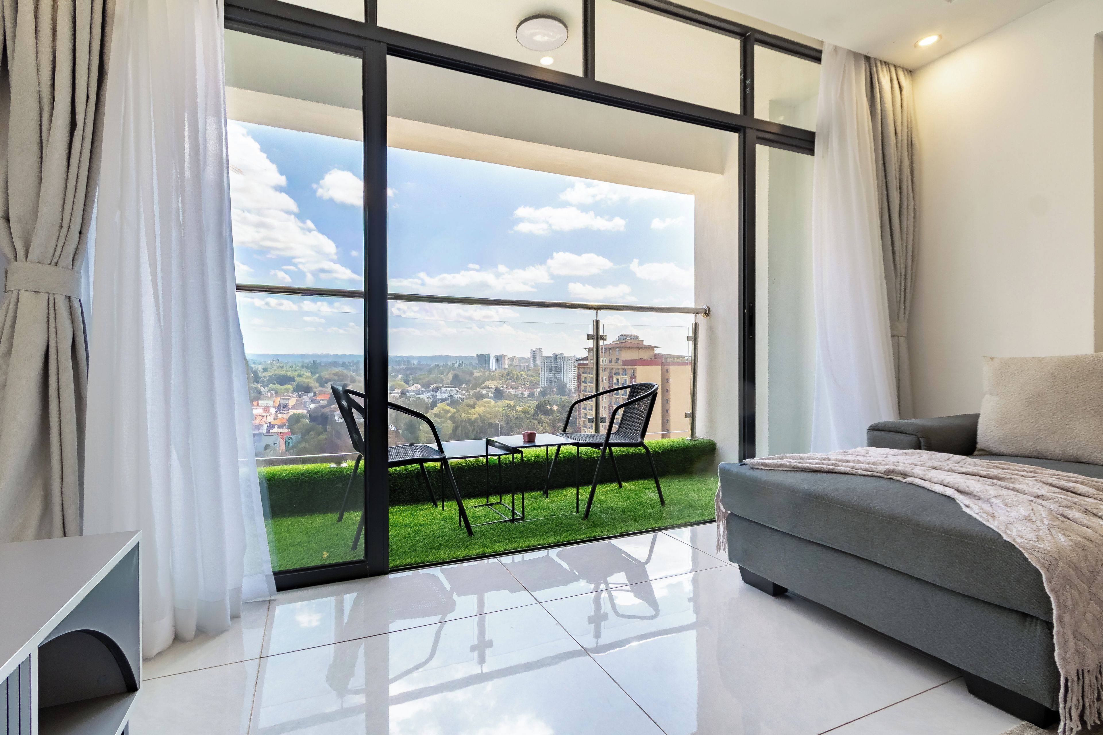 Een moderne slaapkamer met een grote schuifpui die uitkomt op een balkon met uitzicht op een stadsgezicht.