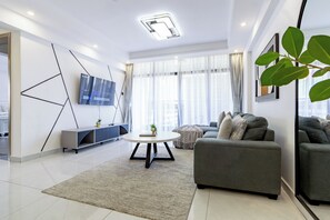 Ein modernes Wohnzimmer mit einem grauen Sofa, einem runden Couchtisch und einem an der Wand befestigten Fernseher.