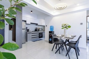 A modern kitchen with a dining area, featuring a water dispenser, a coffee machine, and a large water bottle. - 2BR Shangrila, Westlands Skyline Views-GTC&Sarit (Nairobi)