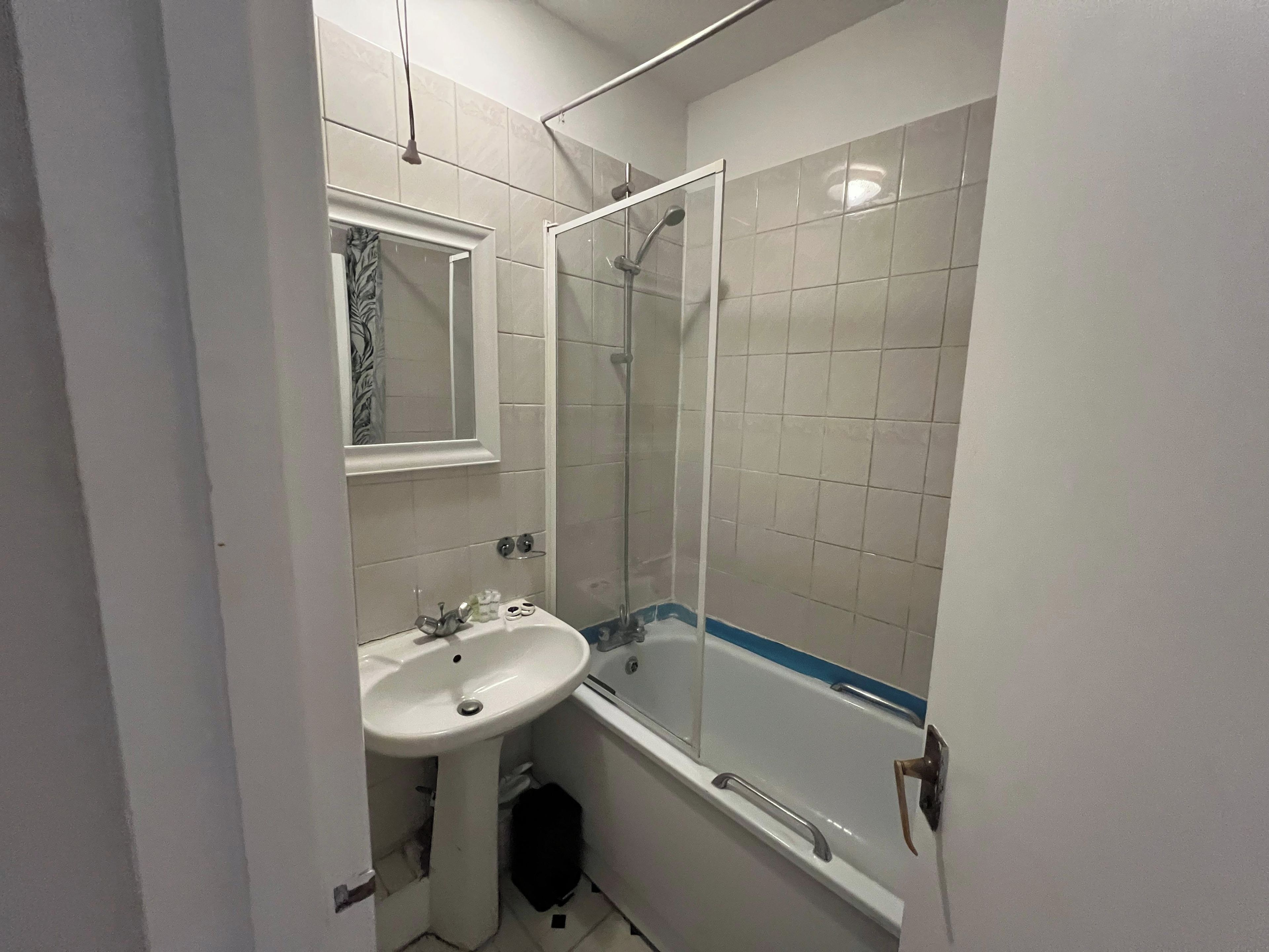 A bathroom with a white sink, mirror, and shower enclosure.