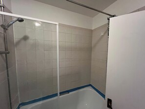 A bathroom with a shower enclosure, a bathtub, and tiled walls.