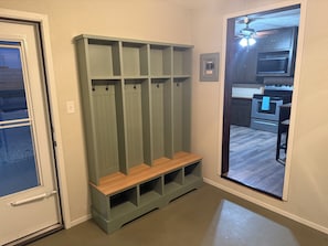 A hallway with a green bench and a door leading to a kitchen area.