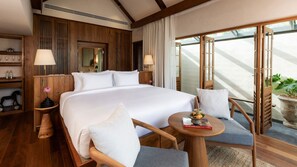A hotel room with a large bed, two bedside tables with lamps, a small round table with a book, and a balcony with a potted plant. - Siritarar Residence by Elite Havens (Lipa Noi)