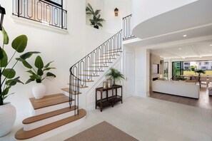 Un intérieur spacieux comprenant un escalier, un espace de vie et une vue sur l’extérieur.