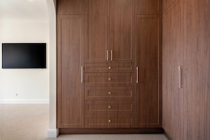 A room with a large wooden wardrobe, a flat-screen TV mounted on the wall, and a carpeted floor. - Isla by Khove - Mermaid Waters (Mermaid Waters)