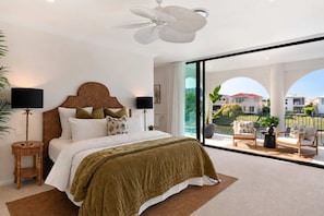 A bedroom with a large bed, a ceiling fan, and a balcony with outdoor furniture. - Isla by Khove - Mermaid Waters (Mermaid Waters)