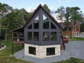 Una casa de dos pisos con cimientos de piedra, ventanas amplias y una terraza.