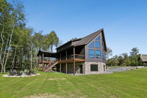 A two-story house with a stone foundation, a balcony, and a deck. - 5-Bedroom Mountain Retreat • Fire Pit • Outdoor Wood-Burning Fireplace (McHenry)