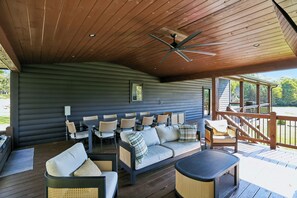Een overdekt terras met een bank, stoelen en een tafel.