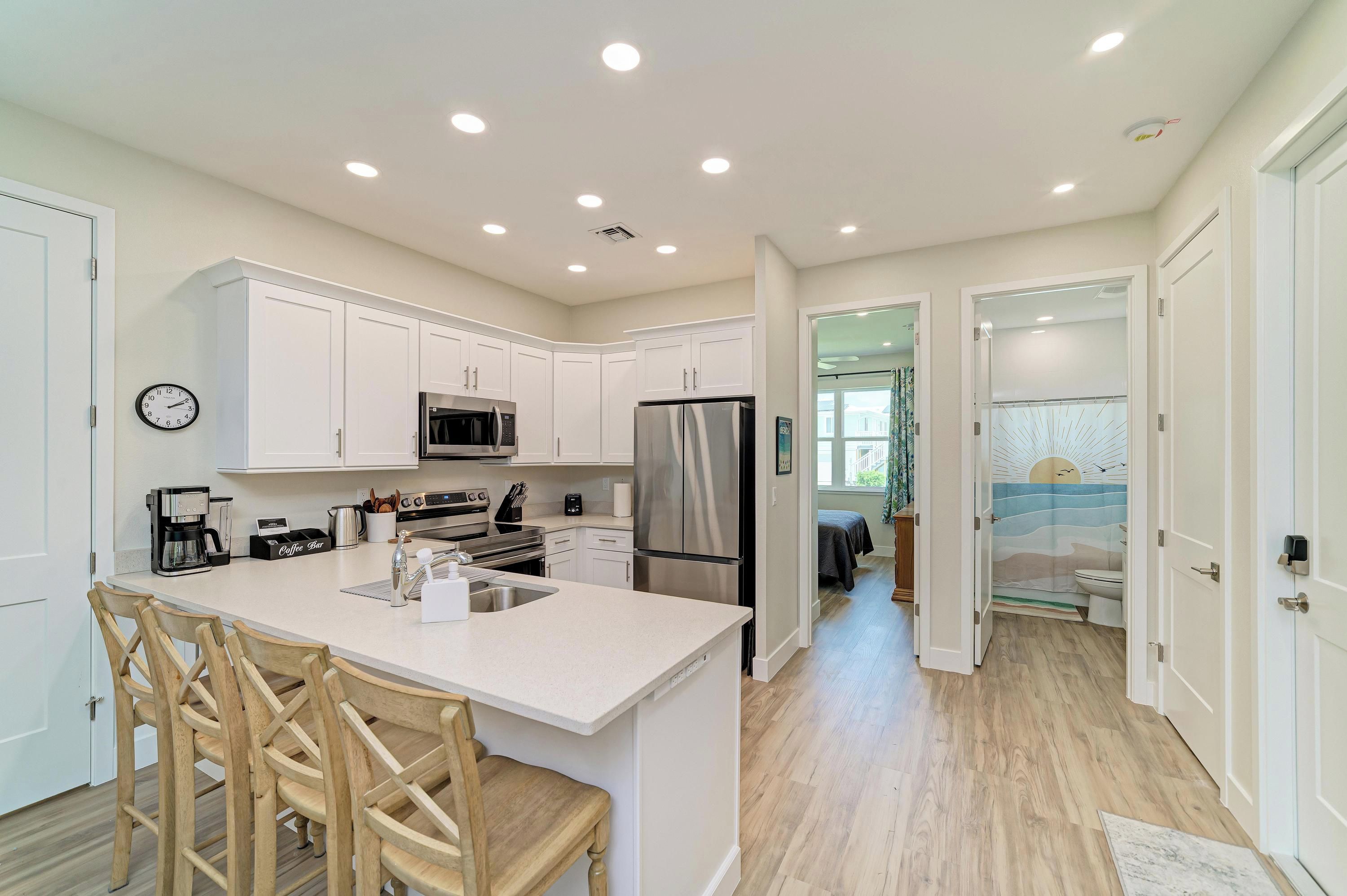 A modern kitchen with white cabinetry, stainless steel appliances, and a central island with seating.