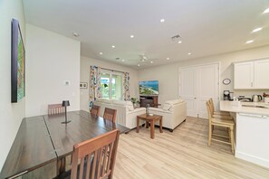 A modern living space with a dining area, sofa, kitchen, and a large window with curtains. - Beachwalk East Side-Near Nokomis Beach (Nokomis)