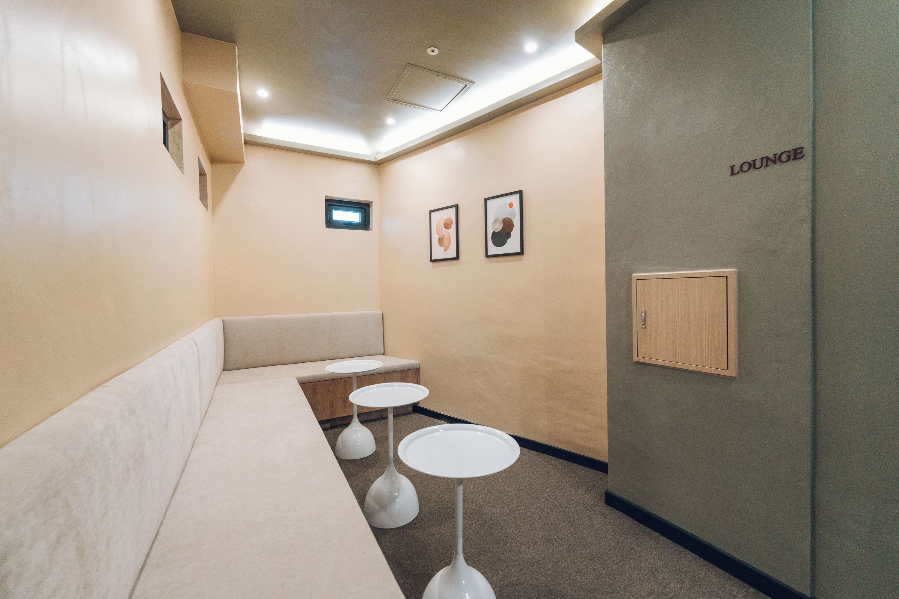 A lounge area with a sofa, two small tables, and a wall-mounted cabinet.
