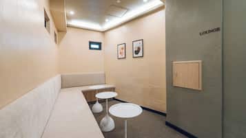 A lounge area with a sofa, two small tables, and a wall-mounted cabinet.