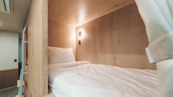 A bunk bed with a headboard, a bedside table, and a wall-mounted light fixture.