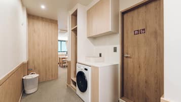 A laundry room with a washing machine, a dryer, and a wooden door with a sign.