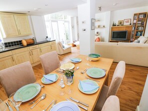 A dining area with a wooden table set for four, surrounded by chairs. - Tall Ships Lower Ground Apartment (Tenby)