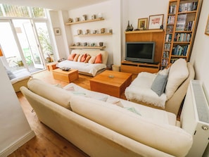 Una sala de estar con sofá, mesa de centro, televisor, estantería y adornos.