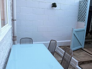 Eine Terrasse mit einem hellblauen Tisch und zwei Korbstühlen.