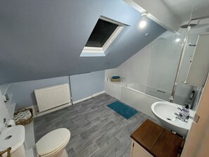 Une salle de bain moderne avec un puits de lumière, une baignoire, un lavabo et des toilettes.