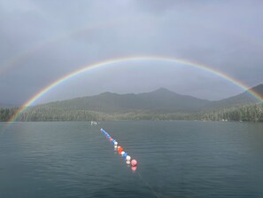 A calm lake with a rainbow and a row of floating buoys.
