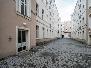 A courtyard with a paved walkway surrounded by multi-story buildings with balconies. - Narutowicza 41 Boutique Apartment #2 (Łódź)