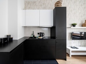 A modern kitchen with black cabinetry, a white countertop, and a built-in stove. - Narutowicza 41 Boutique Apartment #2 (Łódź)