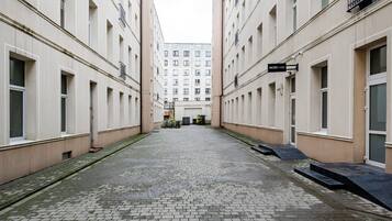 A narrow alleyway between buildings with a paved ground, a sign for 'NODI nails', and a bicycle parked on the right.