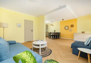 A modern living room with a sofa, a coffee table, and a dining area with chairs and a table. - Ale Fale Trzęsacz Apartment #1 (Trzęsacz)