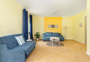 A living room with a blue sofa, a smaller sofa, a coffee table, and a potted plant. - Ale Fale Trzęsacz Apartment #1 (Trzęsacz)