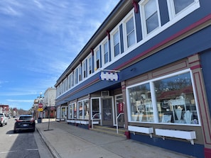 A street view with a row of shops, including a jewelry store with glass display windows. - State + Main Condo | Downtown Luxury Studio (Harbor Springs)