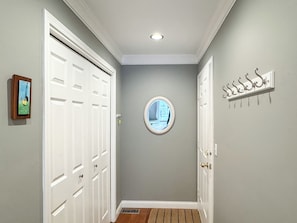 A hallway with a grey wall, a round mirror, and a door with a decorative metal hanger. - Colonial Weque Condo | Views of the Harbor (Harbor Springs)