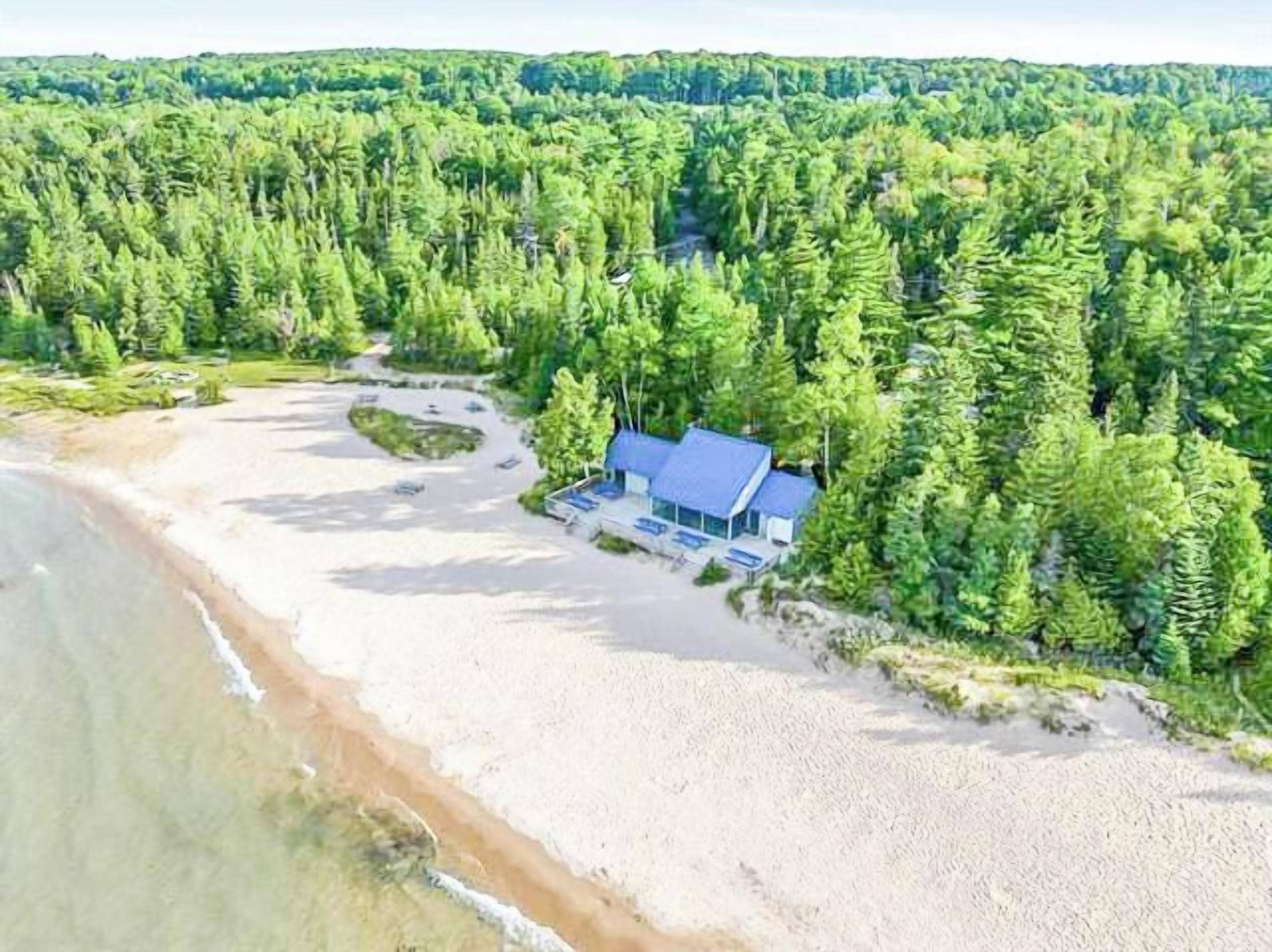 A beachside property with a house, surrounded by dense forest, and a sandy beach.