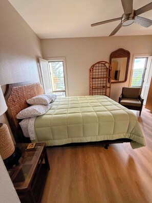 Ein Schlafzimmer mit einem Bett, einem Sessel, einem Deckenventilator und einem Fenster.
