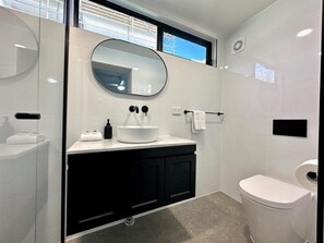 A modern bathroom with a round mirror, a white sink, and a toilet. - Murlong Cres Tallebudgera Creek - 2Bed Waterfront (Gold Coast)