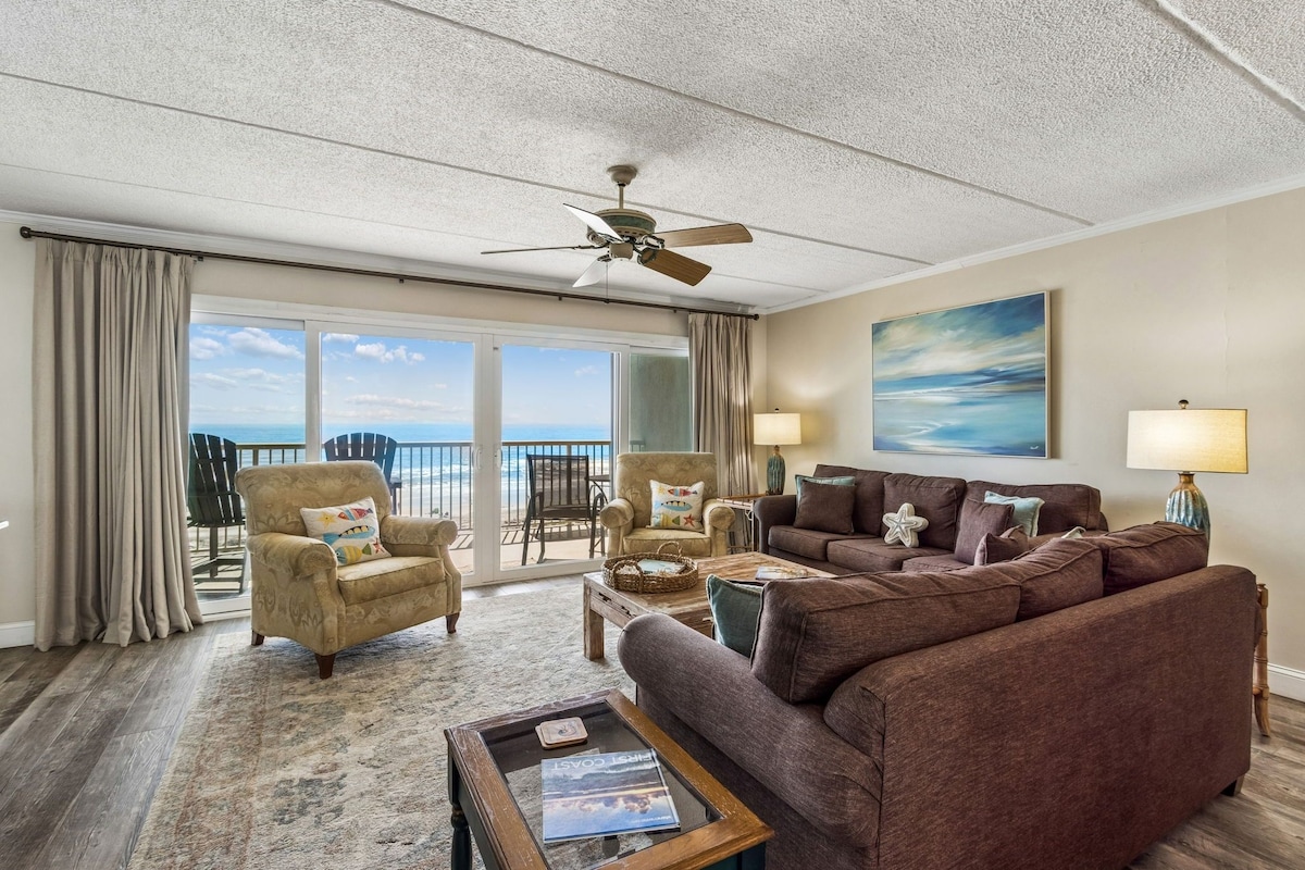A living room with a sofa, armchair, coffee table, and a ceiling fan.