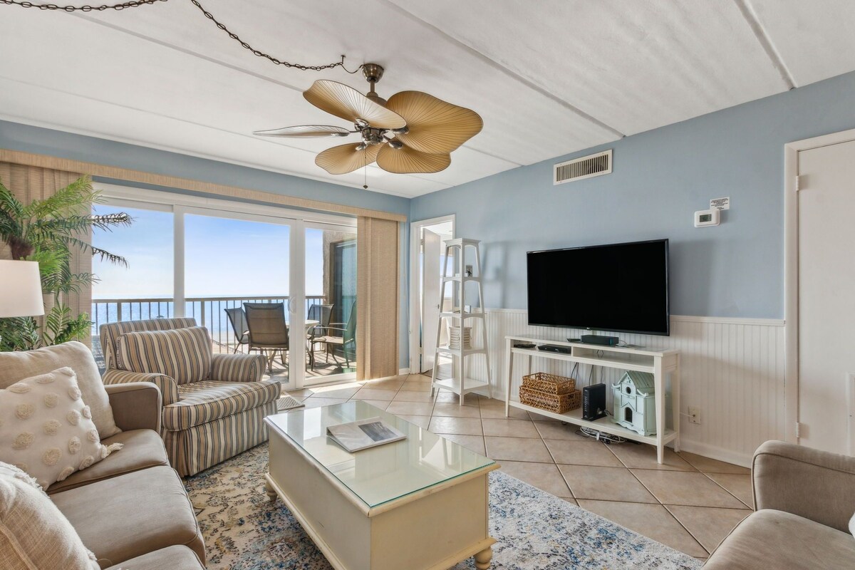 A living room with a TV, sofa, and a ceiling fan.