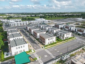 Ein Wohngebiet mit modernen Mehrfamilienhäusern, einer Hauptstraße und einer Grünfläche.